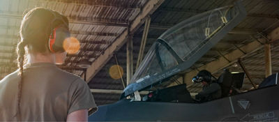 female airman wearing headphones looking at the aircraft